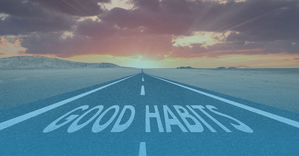 An open road leading into the rising sun with the words "Good Habits" written on the road.