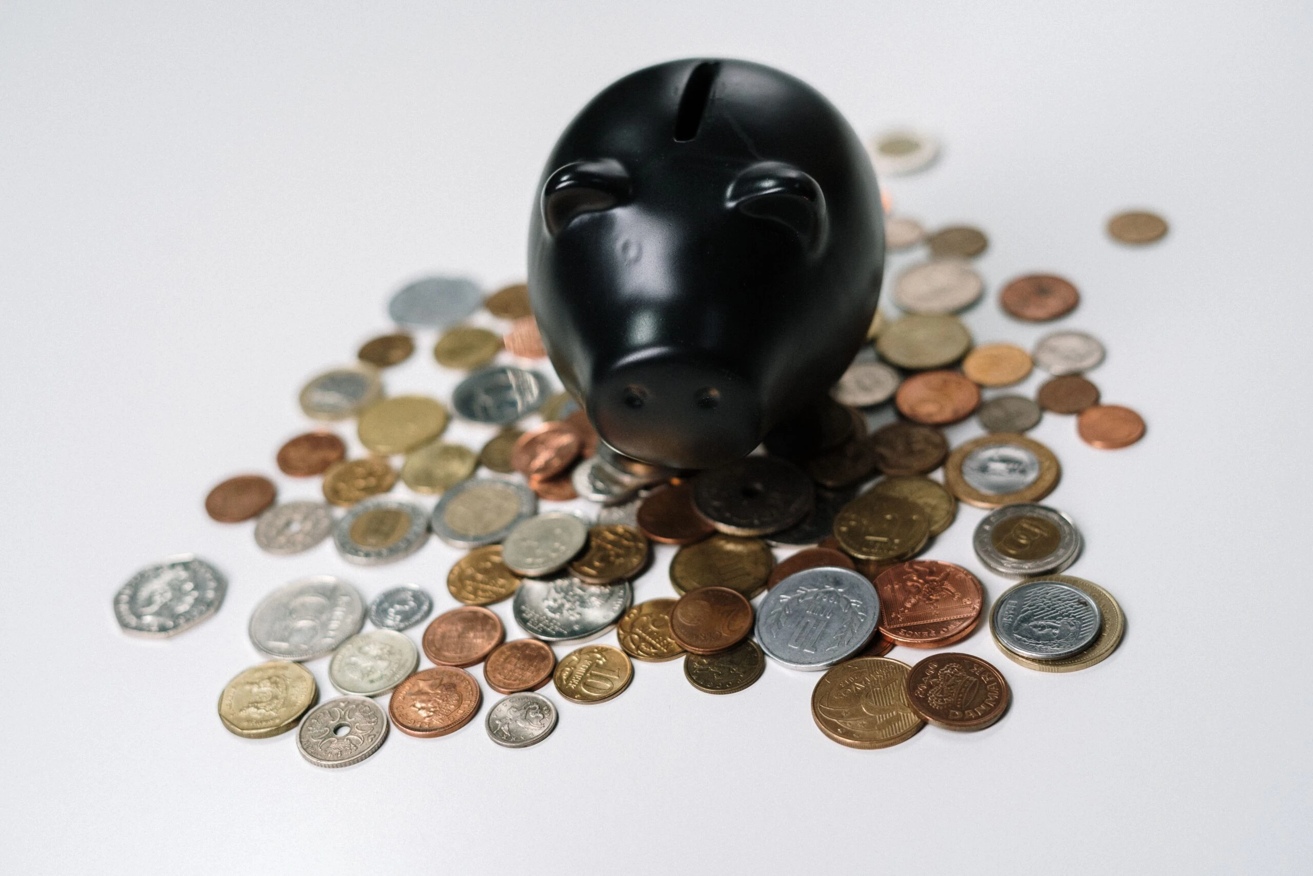 black piggy bank sitting on a pile of coins