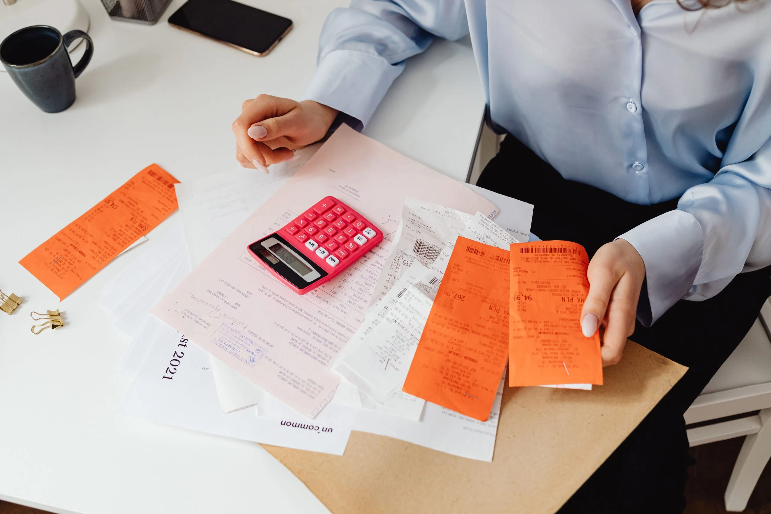 woman holding receipts and looking at a calculator